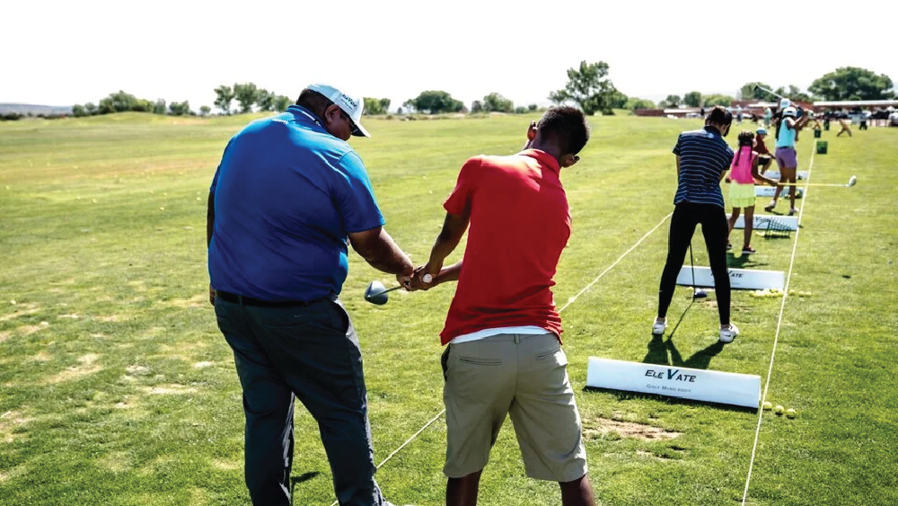 coach and student during golf lessons practicing swinging the golf club